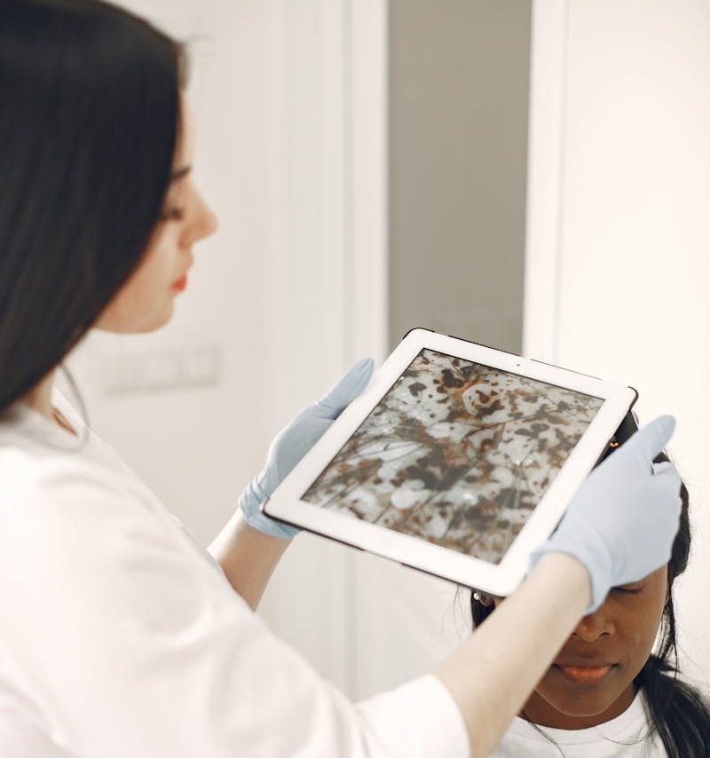 Healthcare professional examining patient's skin using tablet for detailed analysis.