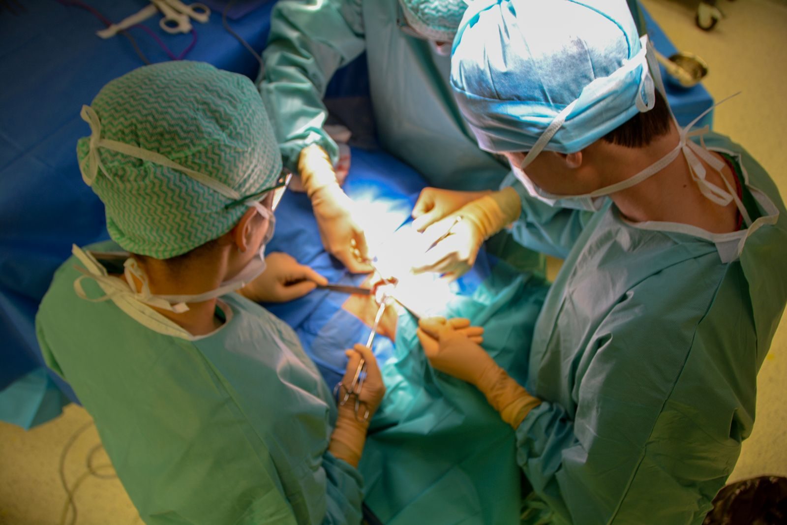 Surgeons in sterile attire performing surgery with precision in a hospital operating room.