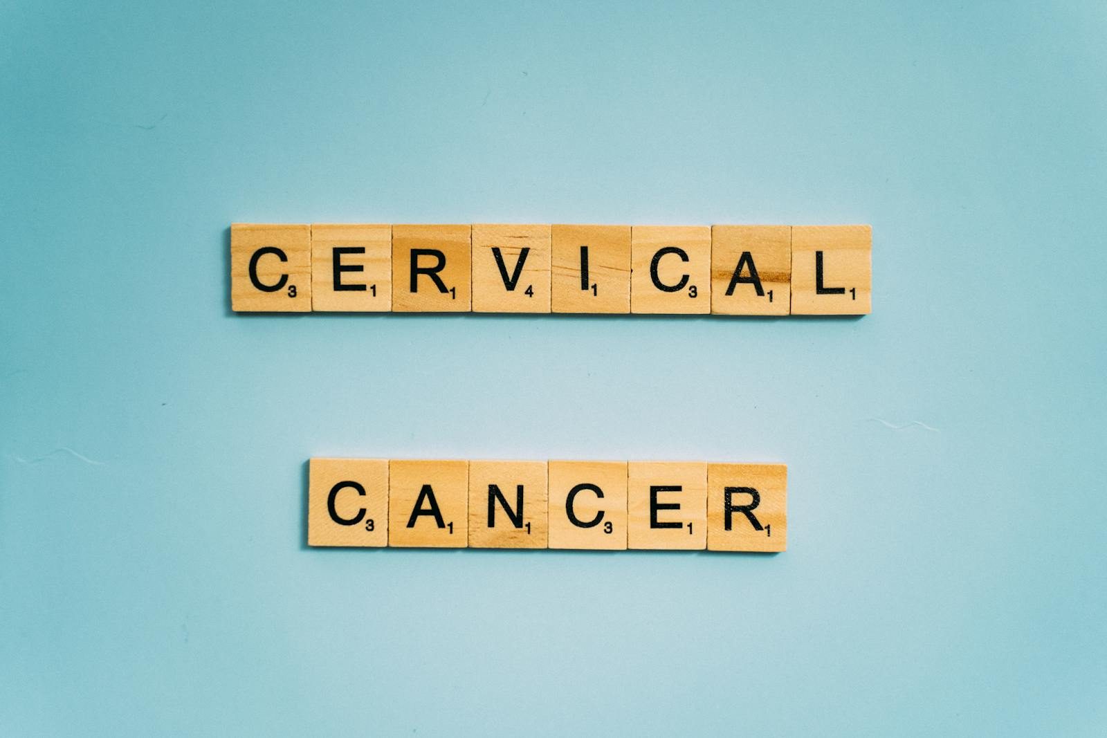 Scrabble tiles spelling 'Cervical Cancer' on a light blue background for awareness.