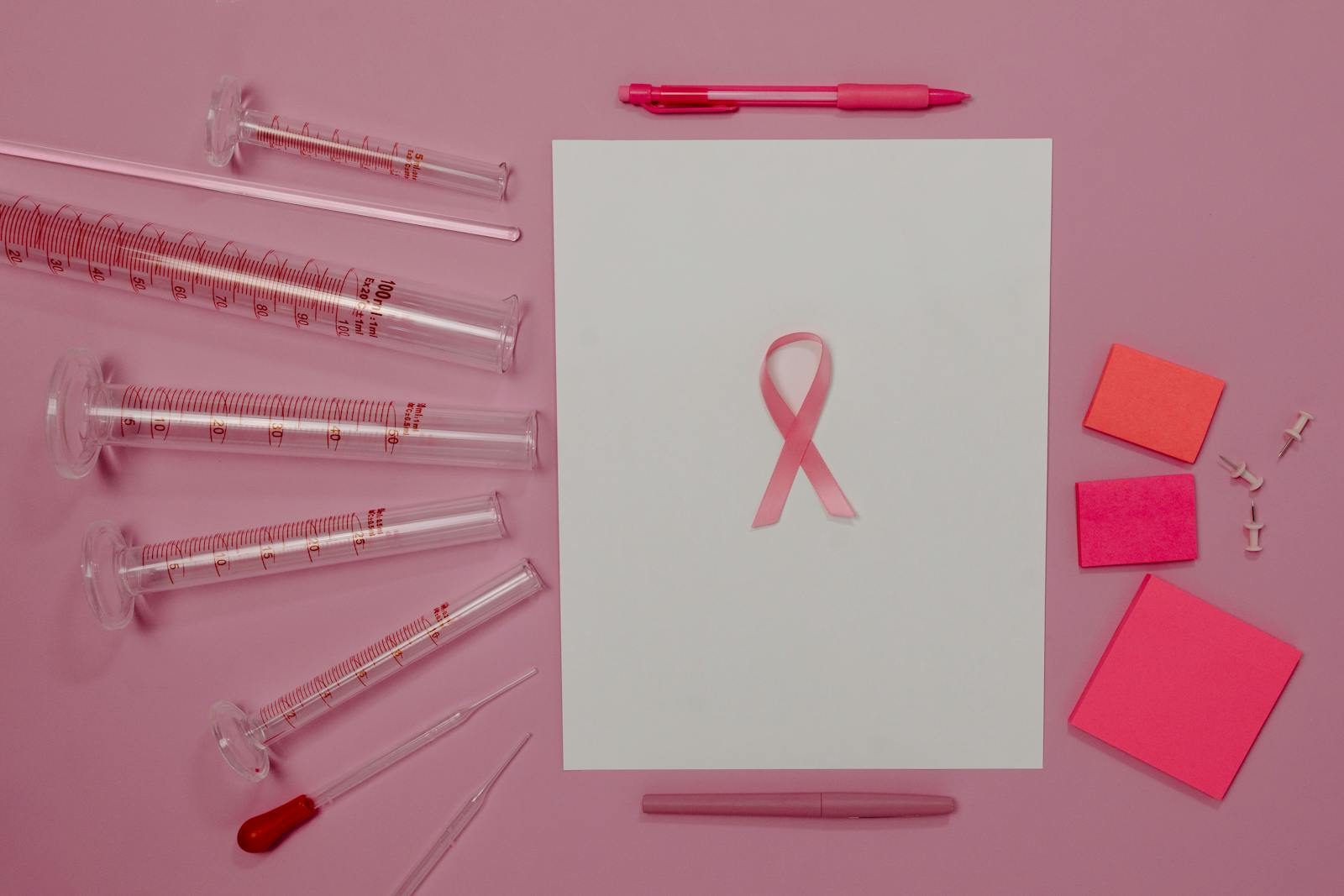 Pink ribbon and lab equipment symbolize breast cancer awareness and research.