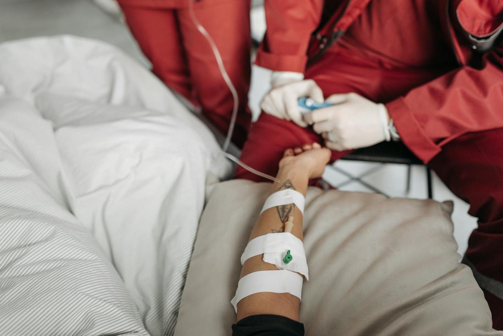Medical staff attending to a patient with an IV drip in a clinical setting.
