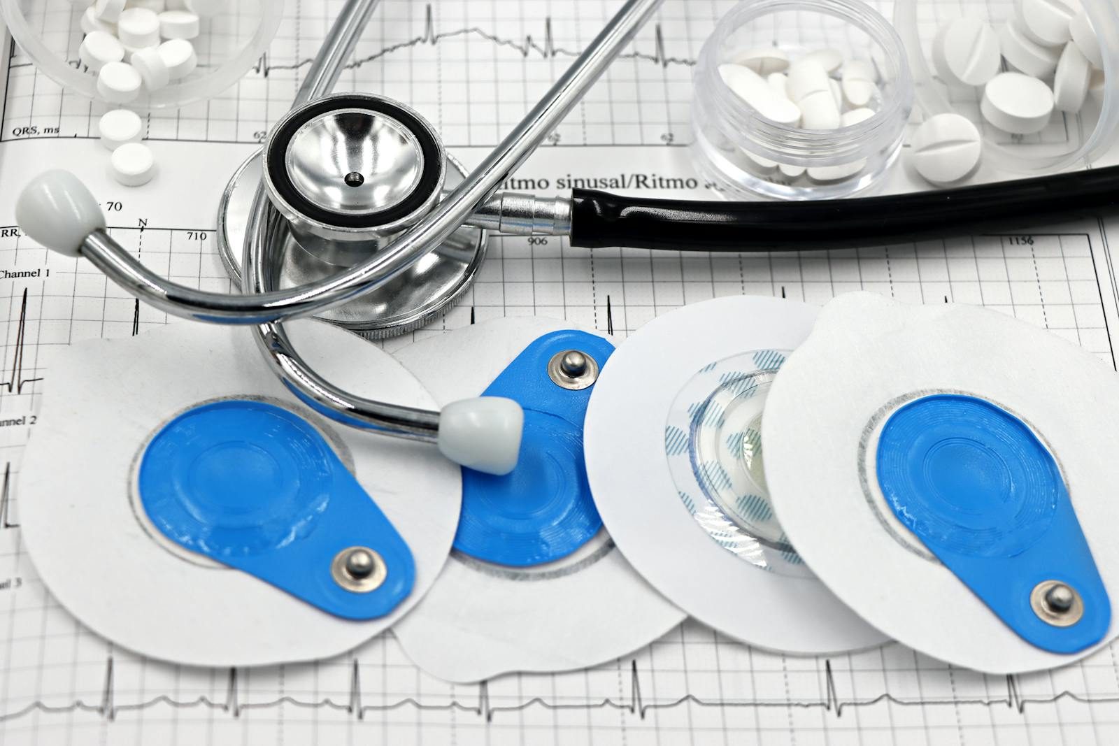 Medical instruments including stethoscope and ECG electrodes on a cardiology chart.