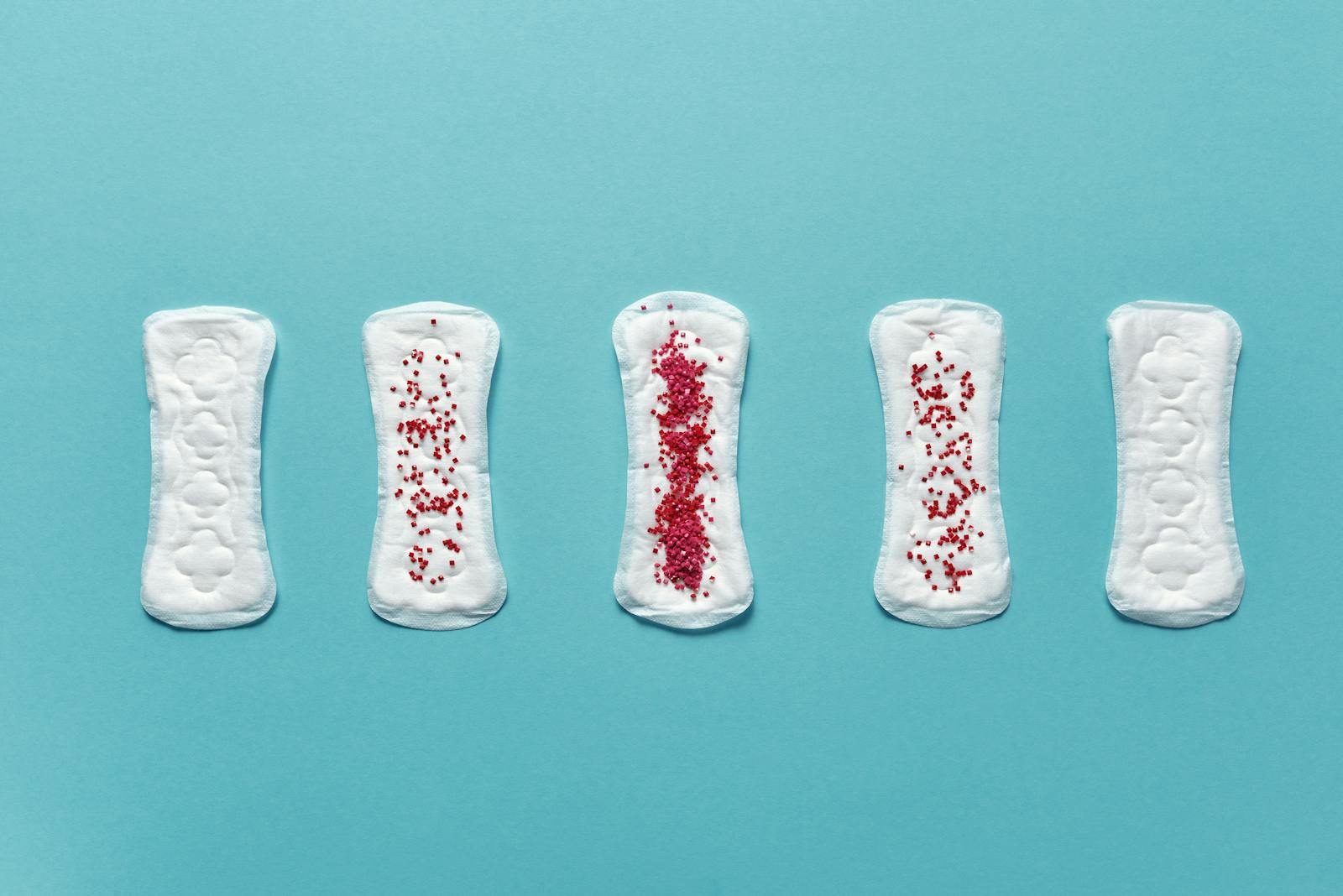 Various menstrual pads arranged on a blue background showcasing stages of use.